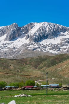 The lush green Sobucimen plateau in spring and the mountains with some melted snow behind.