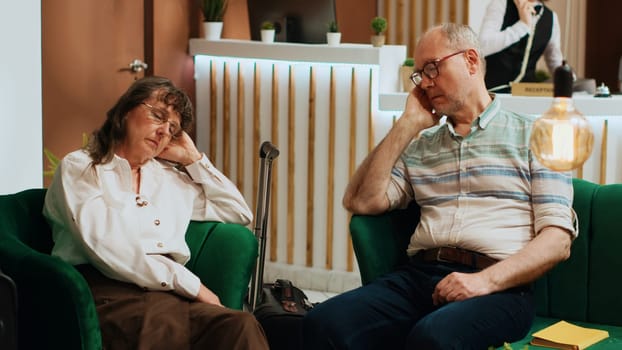 Sleepy old people taking nap on sofa at hotel, feeling tired because of jetlag and travelling by plane. Elderly couple being exhausted and falling asleep in lounge area, arriving at five star resort.