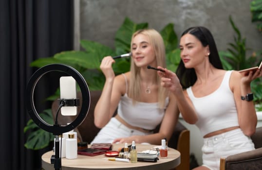 Two beautiful content creator making natural beauty and cosmetic tutorial on green plant garden video. Beauty blogger use camera light ring to show how to beauty care to social medial audience. Blithe