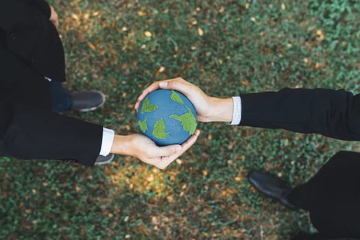 Earth day concept, top view businessman giving Earth globe as CSR corporate social responsible principle to promote environmental awareness and embrace ESG for greener and sustainable future. Gyre