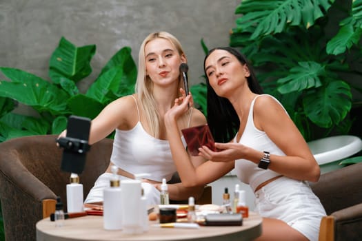 Two beautiful content creator making natural beauty and cosmetic tutorial on green plant garden video. Beauty blogger showing how to beauty care to social medial audience using selfie stick . Blithe