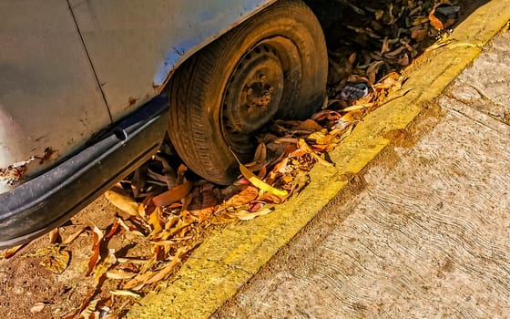 Flat rusted old tire on the car in Zicatela Puerto Escondido Oaxaca Mexico.