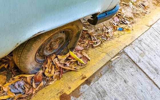 Flat rusted old tire on the car in Zicatela Puerto Escondido Oaxaca Mexico.