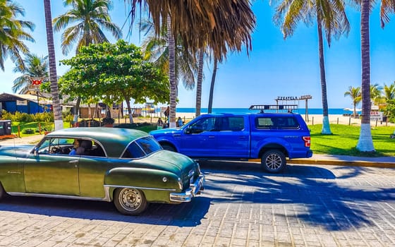 Typical beautiful colorful tourist street road and sidewalk at coast beach with city life cars traffic buildings hotels bars restaurants and people in Zicatela Mexico.