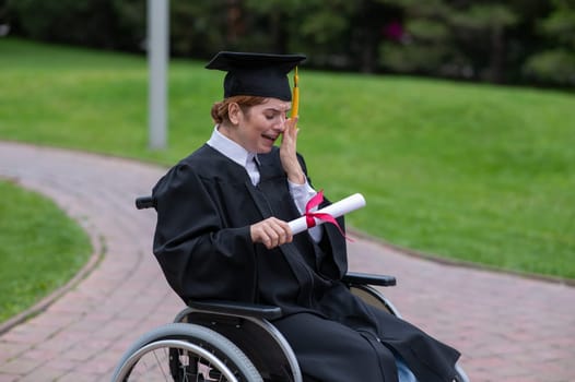 A caucasian woman in a wheelchair holds her diploma and cries with joy outdoors