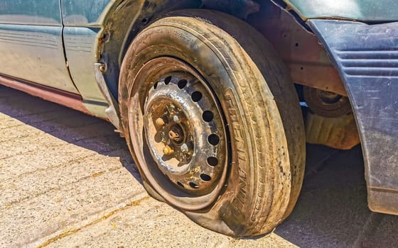 Flat rusted old tire on the car in Zicatela Puerto Escondido Oaxaca Mexico.