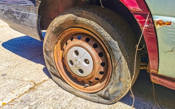 Flat rusted old tire on the car in Zicatela Puerto Escondido Oaxaca Mexico.