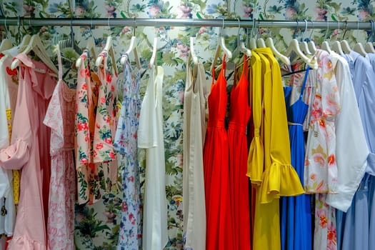 Fashionable womens closet wallpaper with summer dresses and shirts hanging on a rack.