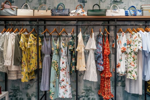 Summer dresses and shirts hanging on a fashionable womens closet wallpaper. Creative concept of a womens clothing showroom.