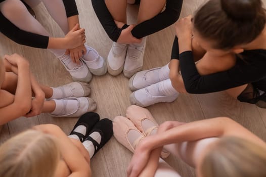 Five little ballerinas and a teacher are sitting in a circle hugging