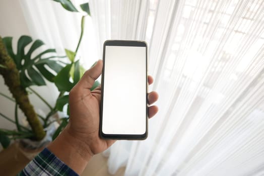 holding smart phone with white screen inside of a home ,