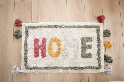 A rectangular rug with the word home written on it lays on the hardwood flooring in the hallway of the building, adding a touch of art to the space