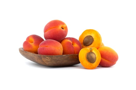 Pile of ripe apricots and one sliced in half to showcase its succulent interior, isolated on a white background