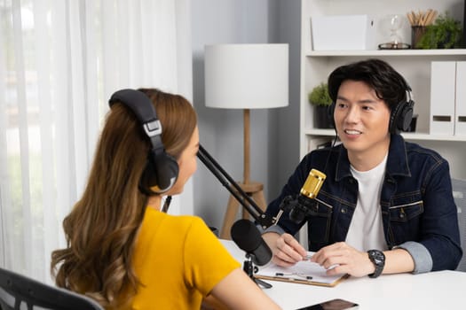 Smiling radio influencer host wearing headphone interviewing woman speaker sharing information to listeners on social media online website live streaming channel at morning at studio record. Infobahn.