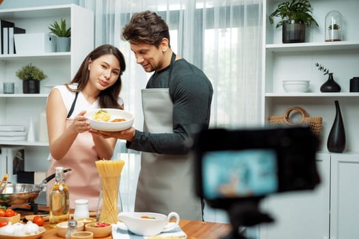 Couple chef influencers completely cooked spaghetti with meat topped with tomato sauce special dish recording on camera with live chanel. Concept of serving healthy food at modern home. Postulate.