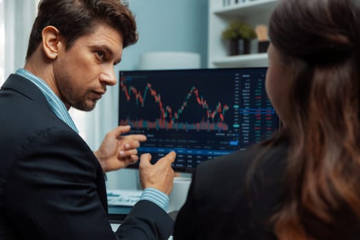 Two business traders discussing on dynamic stock market in currency rate investment trading on two pc screens with compare real time graph on risk or profit point of data at modern office. Postulate.