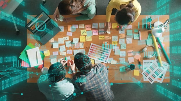 Top down view of business team with casual outfit looking laptop screen and sharing idea. Aerial view of manager works and checking color palette at table with statistic graph holographic. Symposium.