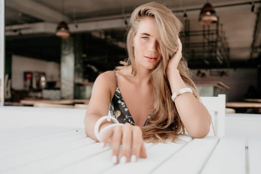 Happy woman portrait in cafe. Boho chic fashion style. Outdoor photo of young happy woman with long hair, sunny weather outdoors sitting in modern cafe