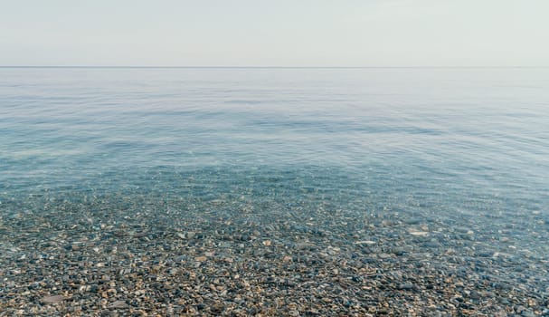 A calm body of water with a few rocks scattered throughout. The water appears to be clear and still, with no visible waves or ripples. The rocks are of various sizes