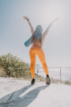 Fitness woman sea. Outdoor workout on yoga mat in park near to ocean beach. Female fitness pilates yoga routine concept. Healthy lifestyle. Happy fit woman exercising with rubber band in park.