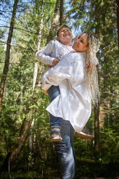 Funny mother with dreadlocks and fat boy happy walking in the forest on a sunny summer day