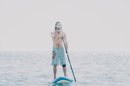 Man Sea Sup. Strong athletic man learns to paddle sup standing on board in open sea ocean on sunny day. Summer holiday vacation and travel concept. Aerial view. Slow motion.