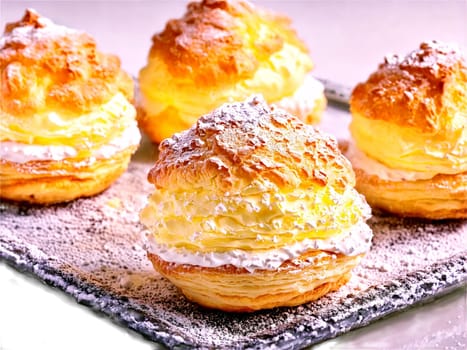 Pastries cream puffs filled with vanilla pastry cream dusted with powdered sugar on a transparent. Food isolated on transparent background.