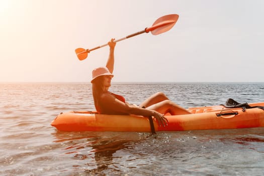 Happy smiling woman in kayak on ocean, paddling with wooden oar. Calm sea water and horizon in background