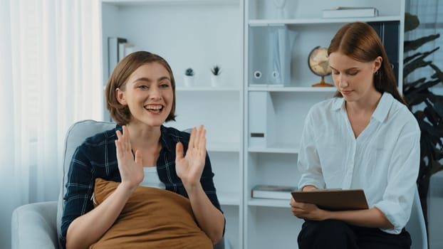 Happy patient and psychologist exchanging mental health conversation in clinic with positive emotion while explaining prim successful work and life to psychologist at psychologist clinic office