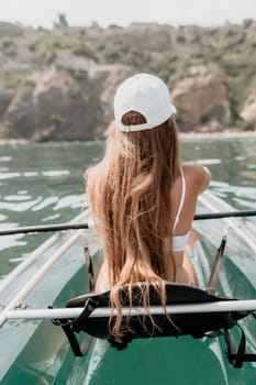 Woman in kayak back view. Happy young woman with long hair floating in transparent kayak on the crystal clear sea. Summer holiday vacation and cheerful female people having fun on the boat.