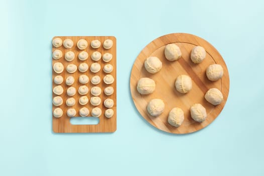 Raw dumplings and manti on wooden boards, semi-finished products top view.