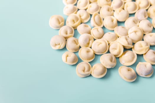 Semi-finished raw dumplings lie on a blue background, copy space.