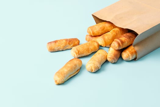 Bagels sticking out of a paper bag on a blue background.