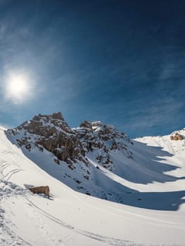 Winter Wonderland: Three rugged peaks stand tall against the snowy landscape, their shadows stretching across the mountain pass. Vertical orientation with place for text.