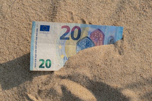 Money 20 euros bills in sandy beach. Concept finance saving money for holiday vacation. Costs in travel holidays. Shadows