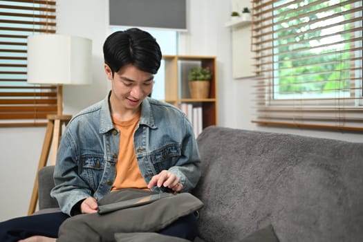 Young man doing online shopping or browsing internet on digital tablet at home.