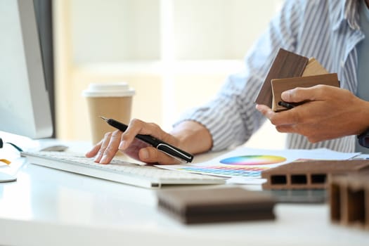 Senior male interior designer choosing material samples working at creative office.