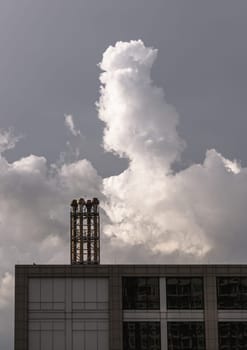 Four chimneys on the flat roof off a big building with fluffy white clouds on sky in the background. Space for text, Selective Focus.