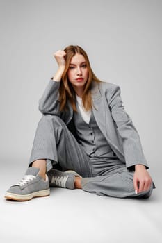 Young Woman in a Gray Suit Sitting on the Floor in Studio portrait