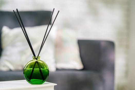 Aroma diffuser bottle with sticks in living room, close up