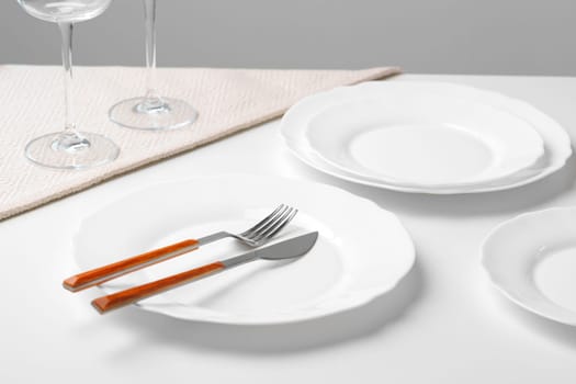 Stylish table setting with white dishware on white tablecloth close up