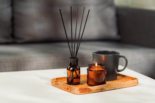 Aromatic reed freshener and candle on table in room close up