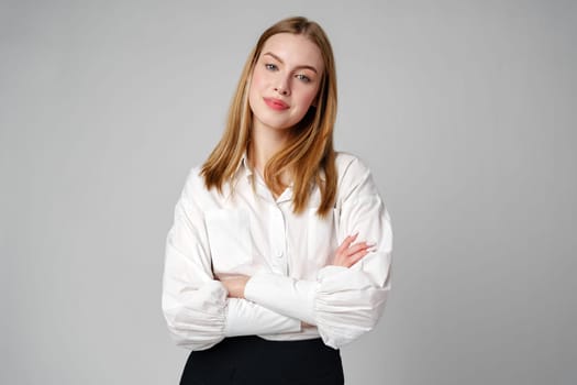 Joyful Young Blonde Woman Smiling against gray background in studio