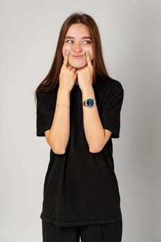 Young Woman Smiling With Hands on Cheeks Against a Gray Background close up