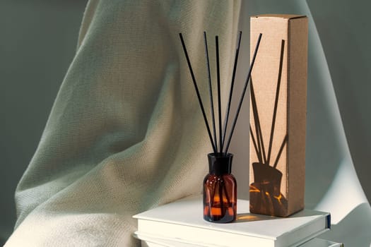 Liquid home perfume in glass diffuser with sticks on chair close up