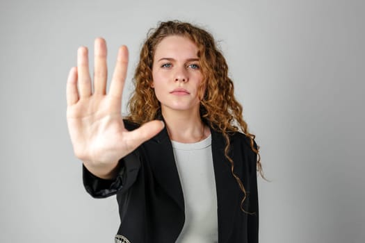 Woman With Curly Hair Holding Hand Up in Studio