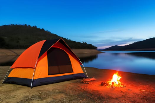 orange tourist tent on the shore of a lake next to a burning bonfire in the evening.