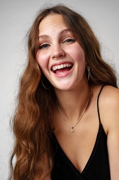 A woman with long hair is smiling while wearing a black dress. She exudes confidence and elegance in her attire.