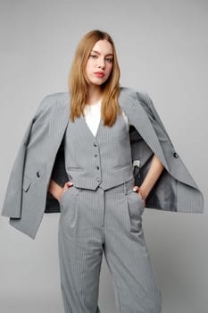 Woman in Gray Suit and White Shirt posing in studio on gray background