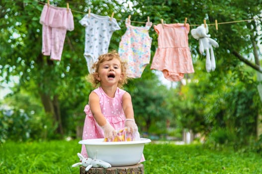 The child washes clothes and toys. Selective focus. Kid.